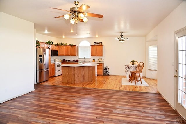 kitchen with electric stove, a center island, light countertops, black microwave, and stainless steel refrigerator with ice dispenser