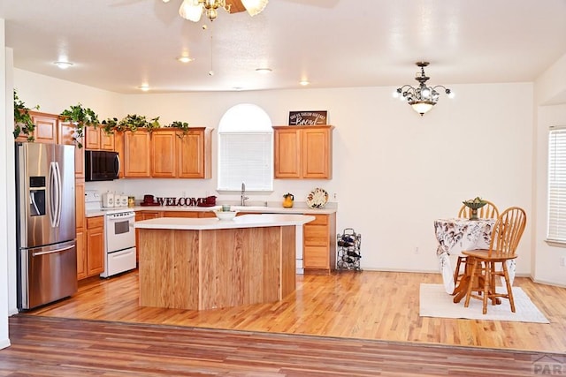 kitchen featuring white electric range oven, a center island, light countertops, light wood-type flooring, and stainless steel refrigerator with ice dispenser