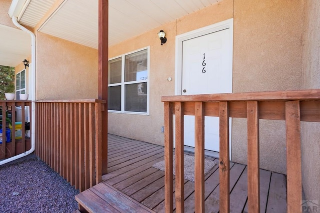 doorway to property featuring a wooden deck and stucco siding