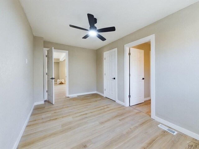 unfurnished bedroom with light wood-type flooring, visible vents, ceiling fan, and baseboards