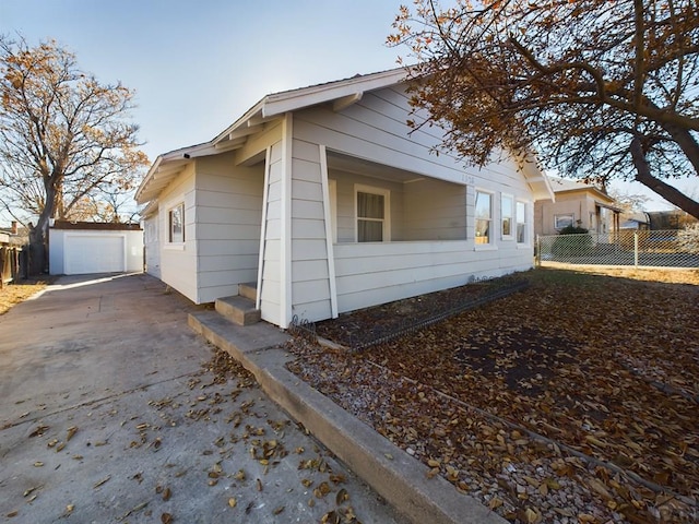 view of side of property with driveway, an outdoor structure, fence, and a detached garage