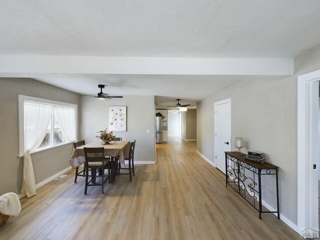 dining room featuring baseboards, a textured ceiling, and light wood finished floors