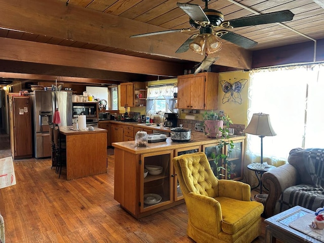 kitchen featuring stainless steel appliances, brown cabinetry, a kitchen island, wood finished floors, and wooden ceiling