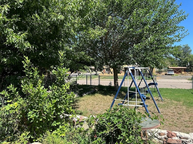 view of jungle gym featuring fence and a lawn