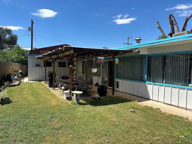 rear view of house featuring a yard, fence, and a patio