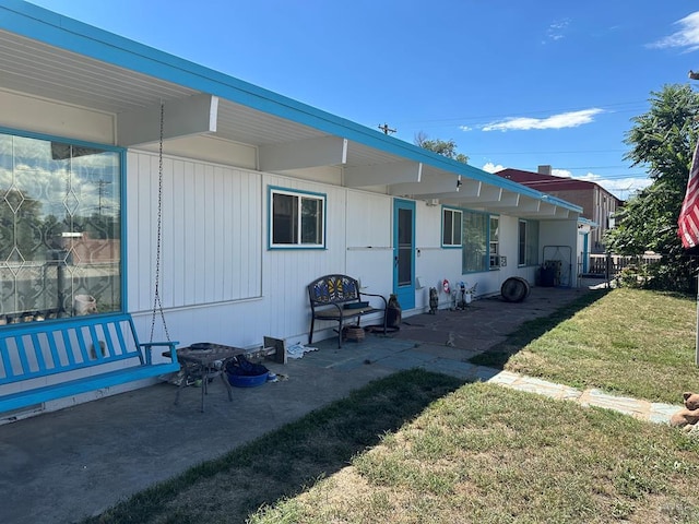 back of property featuring a lawn and a patio