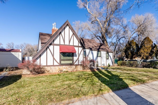 view of front of property with stucco siding, a front lawn, and a chimney