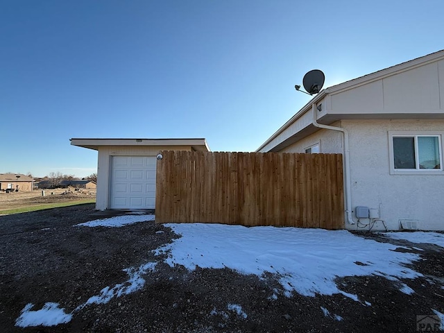 yard covered in snow featuring a garage and fence