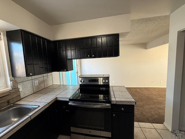 kitchen with tile countertops, electric range, and dark cabinetry