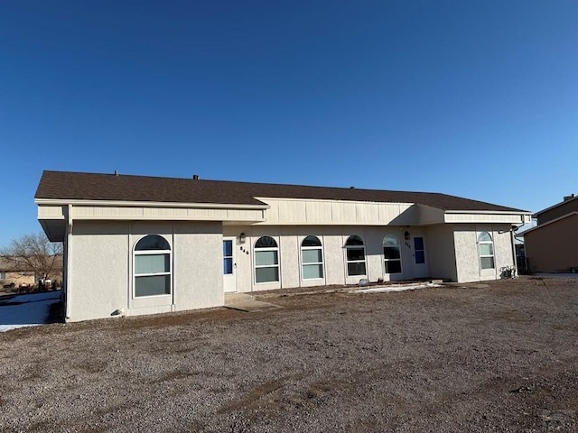 rear view of house featuring stucco siding