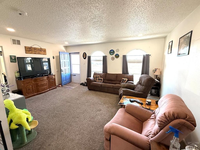 living area with a healthy amount of sunlight, a textured ceiling, visible vents, and carpet flooring