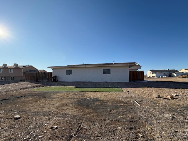 rear view of house featuring fence and stucco siding