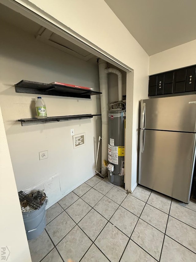 kitchen with water heater, light tile patterned flooring, freestanding refrigerator, and dark cabinets