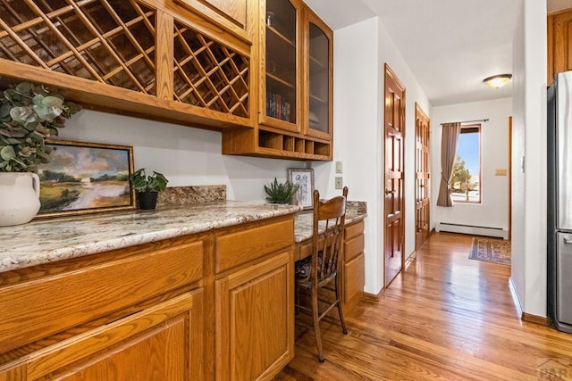 interior space with a baseboard radiator, freestanding refrigerator, and light wood finished floors