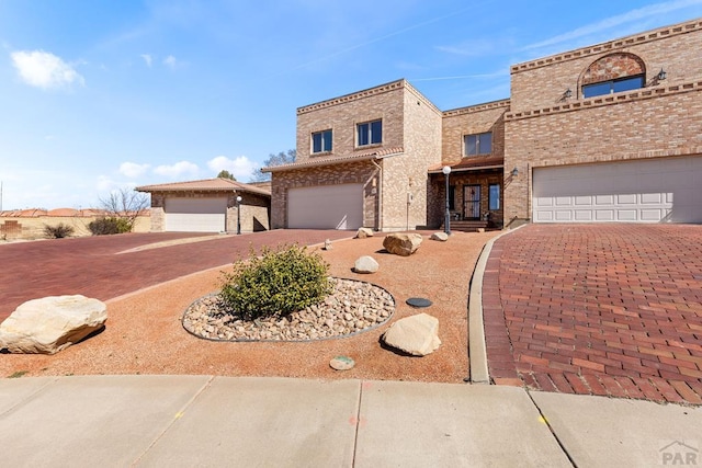 view of front of property featuring brick siding, an attached garage, and decorative driveway