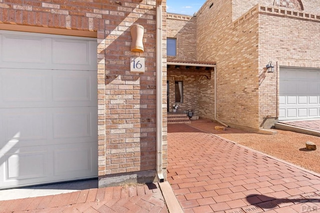 doorway to property featuring brick siding and a garage