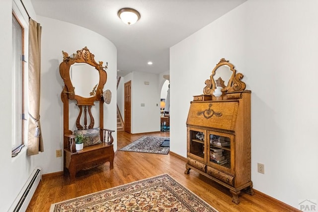 hall with stairs, wood finished floors, baseboards, and a baseboard radiator