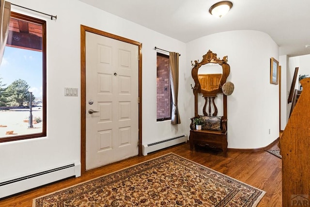 foyer with a baseboard heating unit, wood finished floors, and baseboards