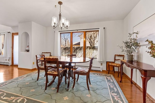 dining room with baseboard heating, an inviting chandelier, and wood finished floors