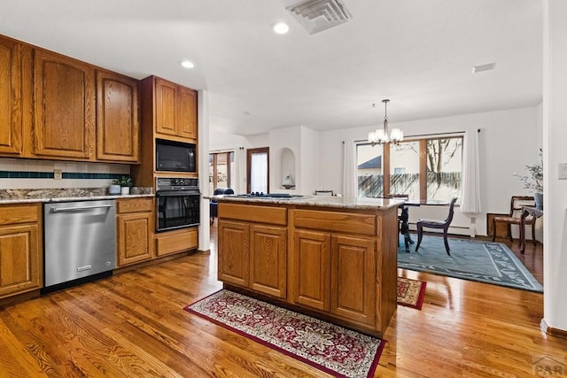 kitchen with wood finished floors, visible vents, an inviting chandelier, black appliances, and brown cabinets