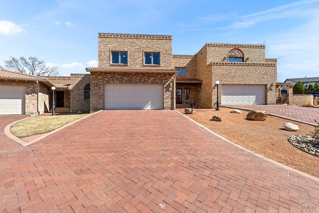 view of front of house with brick siding, an attached garage, and decorative driveway