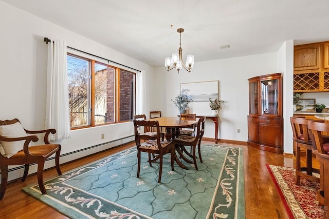 dining space with a notable chandelier, baseboards, and wood finished floors