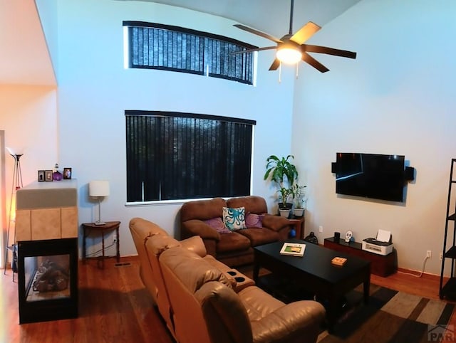 living room featuring a ceiling fan, a tile fireplace, and wood finished floors