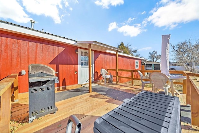 wooden deck with outdoor dining area and a grill