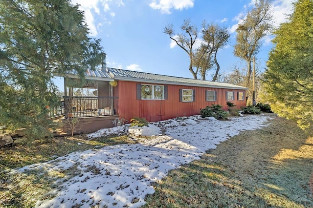 view of snow covered exterior with covered porch and metal roof