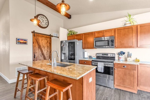 1216 N Whitetail Pl, Pueblo, CO 81007 - kitchen featuring appliances with stainless steel finishes, a sink, light wood finished floors, brown cabinetry, and beam ceiling
