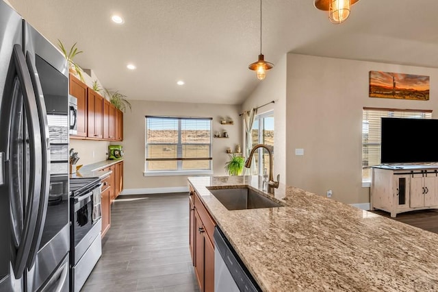 kitchen with light stone counters, brown cabinets, hanging light fixtures, stainless steel appliances, and a sink