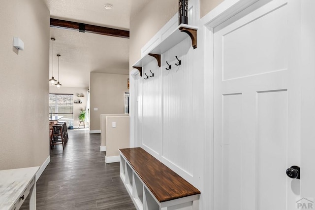 mudroom featuring baseboards, dark wood finished floors, and beam ceiling