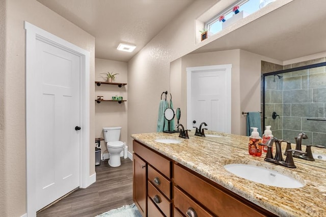 1216 N Whitetail Pl, Pueblo, CO 81007 - bathroom featuring double vanity, wood finished floors, a tile shower, toilet, and baseboards