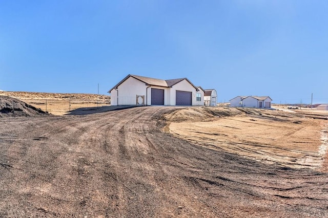 view of front facade featuring a garage, fence, and stucco siding