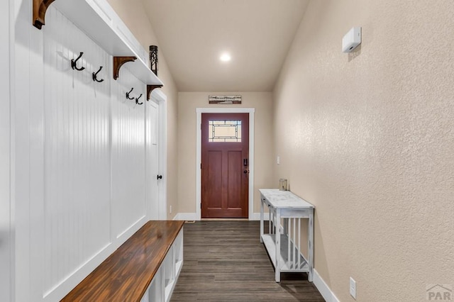 mudroom with a textured wall, dark wood-style flooring, and baseboards