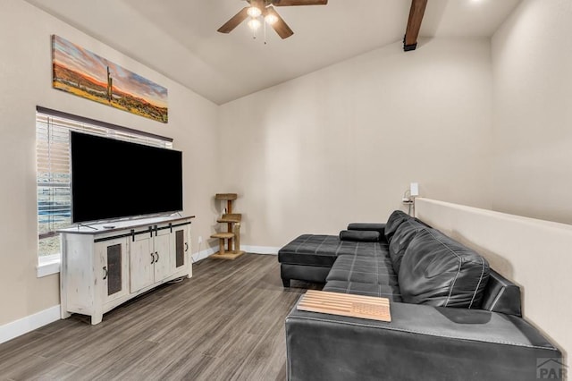 living area with ceiling fan, vaulted ceiling with beams, baseboards, and wood finished floors