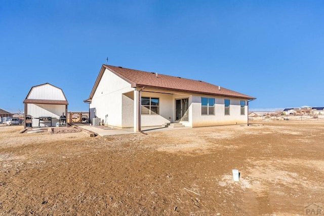 back of property with central AC unit, roof with shingles, a patio area, and stucco siding