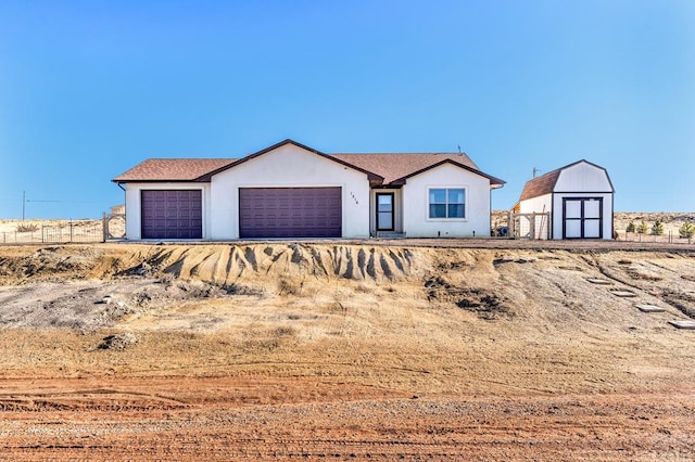 view of front of property with a garage, a shed, an outbuilding, and stucco siding