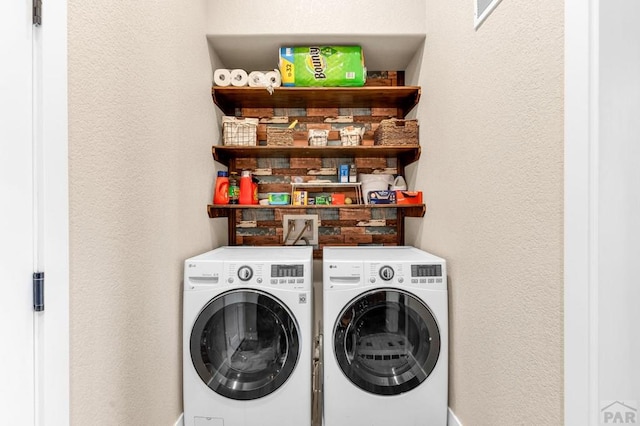 washroom with laundry area, a textured wall, and washing machine and clothes dryer