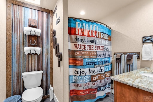 full bathroom featuring a textured wall, toilet, vanity, wood finished floors, and a shower with curtain