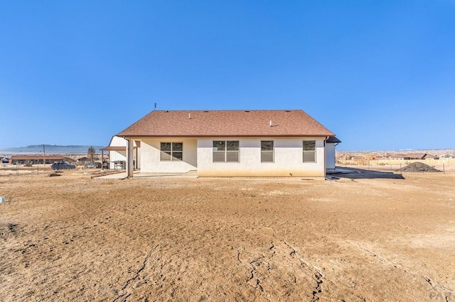 back of house featuring a shingled roof, fence, a patio, and stucco siding