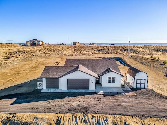 view of front of house with roof with shingles, stucco siding, a storage shed, a garage, and an outdoor structure