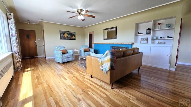 316 N Hooper Ave, Walsenburg, CO 81089 - living room featuring wood finished floors, radiator, ceiling fan, a fireplace, and ornamental molding