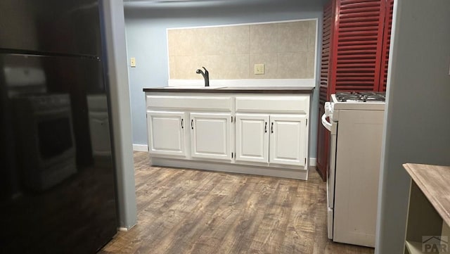 316 N Hooper Ave, Walsenburg, CO 81089 - kitchen featuring gas range gas stove, white cabinets, wood finished floors, and decorative backsplash