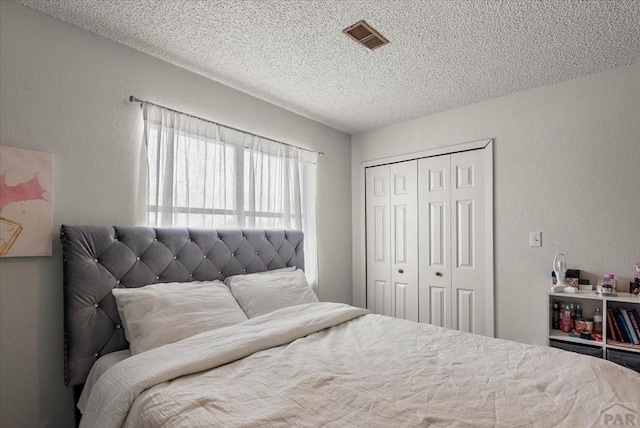 bedroom with a closet, visible vents, a textured wall, and a textured ceiling