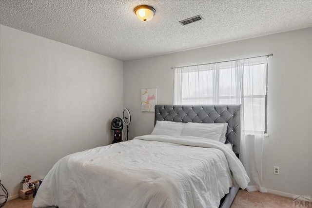 carpeted bedroom featuring a textured ceiling, visible vents, and baseboards