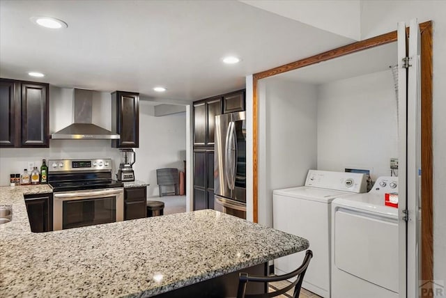 kitchen featuring washing machine and dryer, dark brown cabinetry, recessed lighting, stainless steel appliances, and wall chimney range hood