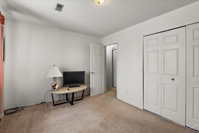 bedroom featuring a textured ceiling, a closet, visible vents, and light colored carpet