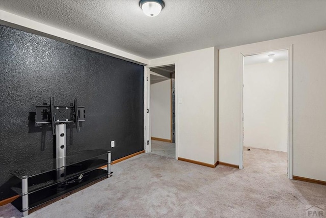 exercise room with light carpet, baseboards, and a textured ceiling