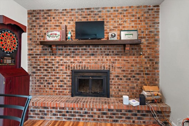 details featuring a brick fireplace, a textured ceiling, and wood finished floors